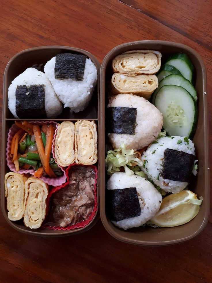 two trays filled with different types of food on top of a wooden table next to each other