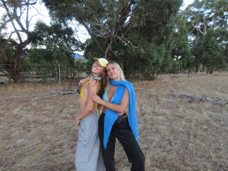 two women standing next to each other in a field