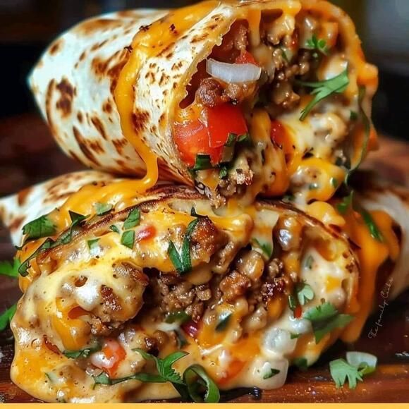 two burritos stacked on top of each other with cheese, meat and vegetables