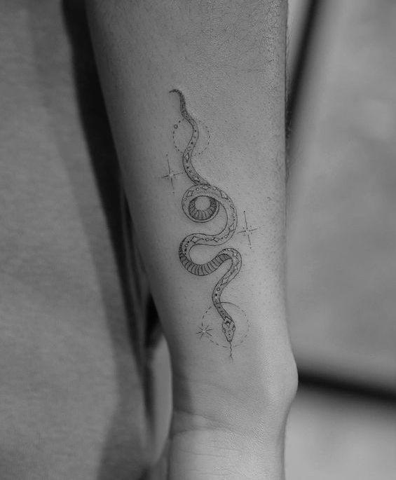 a snake tattoo on the arm is shown in this black and white photo with stars