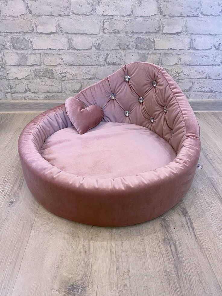 a pink dog bed on the floor in front of a brick wall