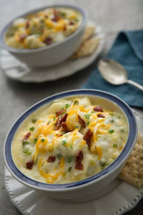 two bowls of potato soup with crackers on the side