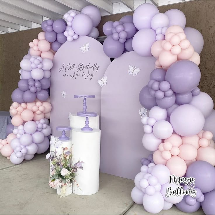 there is a large balloon arch with flowers and balloons on the wall next to it