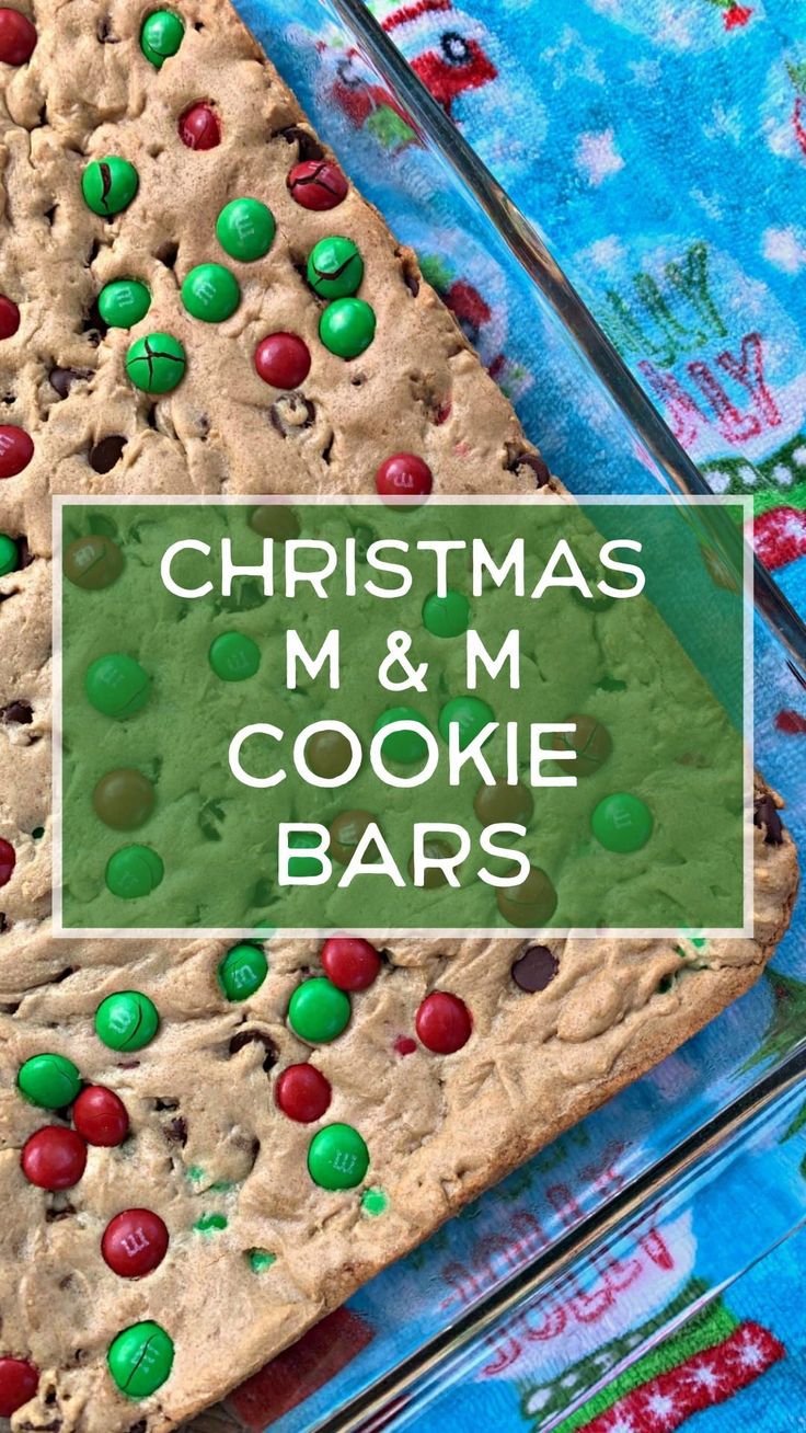 christmas m & m cookie bars with green and red candies in the middle on a blue tablecloth