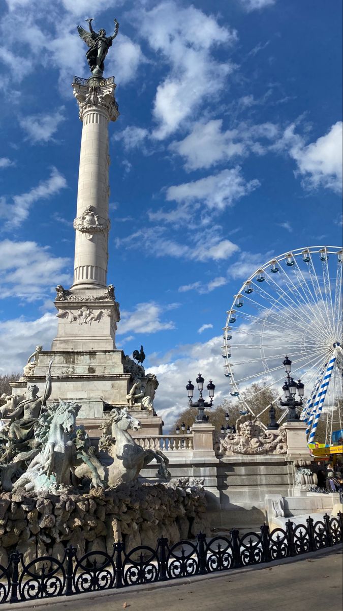 the statue is surrounded by many statues and ferris wheel in the background with blue sky