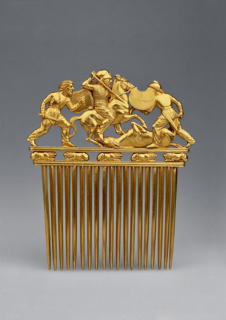 an antique gold comb with horses and riders on it