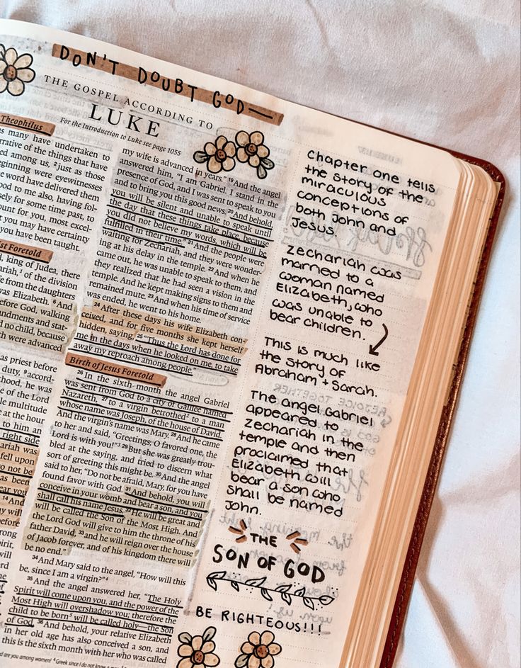 an open bible with handwritten words and flowers on the pages, laying on a white sheet