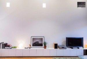 a living room filled with furniture and a flat screen tv on top of a white shelf