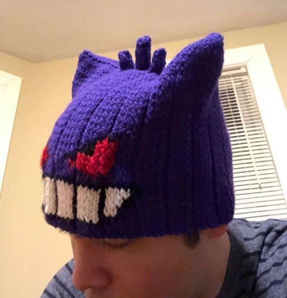 a man wearing a purple knitted hat with red and white teeth