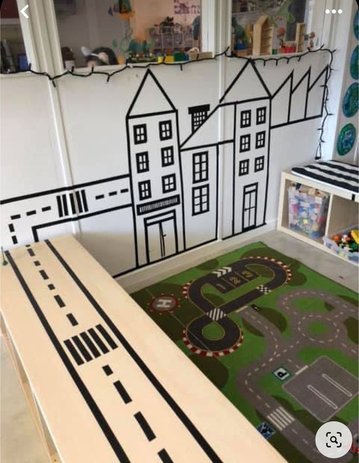 a play area with a train track and toy houses on the wall next to it