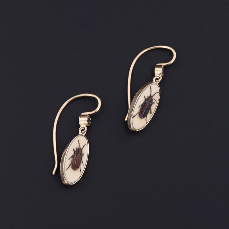 Add a touch of intrigue to any ensemble with these unique insect earrings! To create these earrings, our jeweler carefully cut antique shibayama game pieces (circa 1880) into an oval shape, mounted them in 14k gold, and added 14k ear wires and sapphire surmounts. Each earring measures 1 inch from the top of the ear wire to bottom by 0.3 inches wide, and they are in excellent condition. Materials: Sapphire, Gold. Collectible Oval Matching Earrings, Oval Matching Earrings For Collectibles, Victorian Oval Earrings For Collectors, Collectible Victorian Oval Earrings, Antique Brass Oval Earrings, Antique Oval Brass Earrings, Victorian Oval Pierced Earrings, Victorian Jewelry With Oval Matching Earrings, Antique Oval Earrings