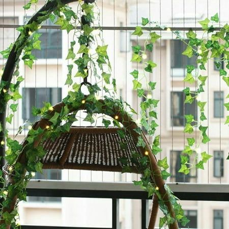 a green plant hanging from the side of a window next to a basket with lights on it