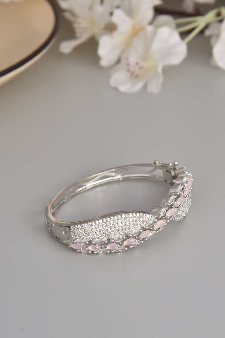 Embrace the soft elegance of our Blush Bloom Bracelet, a delicate ode to feminine beauty. Crafted from durable brass and adorned with shimmering CZ stones, this bracelet captures the essence of grace and sophistication. Finished in radiant rhodium, the gentle pink CZ stones evoke the tender bloom of spring flowers, infusing your look with a touch of natural charm. Each stone radiates with a subtle sparkle, casting a luminous glow that captivates the senses. Let this exquisite bracelet grace your Hand Set Elegant Crystal Bracelet, Pink Bracelets With Diamond Accents For Gift, Pink Bracelets With Diamond Accents As A Gift, Silver Crystal Bracelet Hand Set, Pink Hand Set Bracelets, Elegant Pink Crystal Bracelet For Formal Events, Pink Hand-set Bangle Jewelry, Elegant Pink Diamond Bracelet With Diamond Accents, Elegant Pink Crystal Bracelet With Sparkling Stones