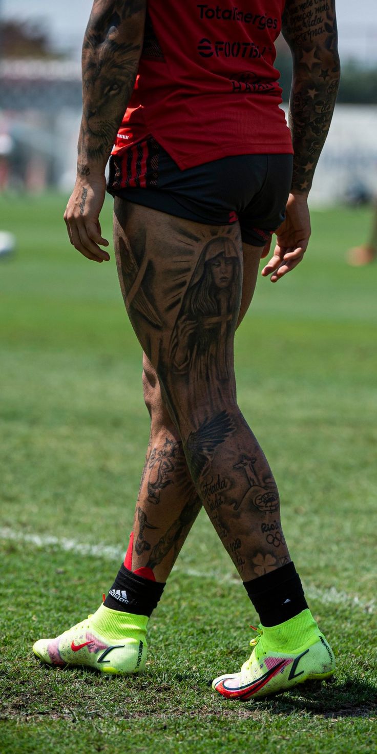 a man with tattoos standing on top of a soccer field