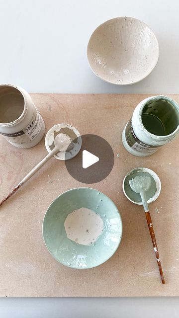 bowls and paintbrushes are sitting on a table with two empty cups next to them