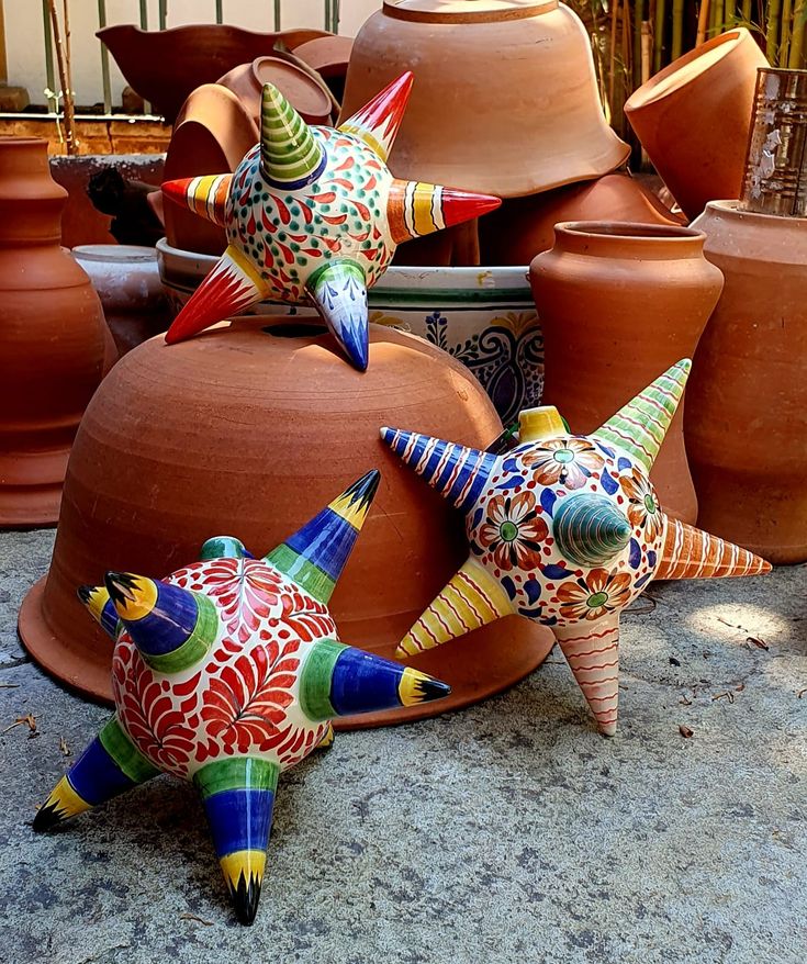 three colorful ceramic starfishs sitting next to each other on top of clay pots