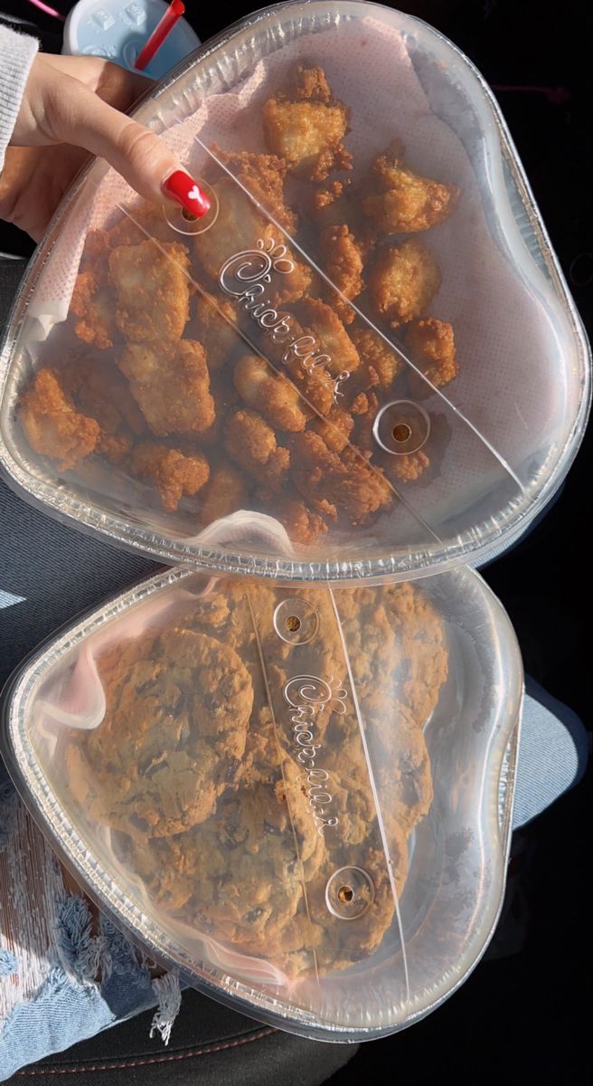 two plastic containers filled with fried food on top of a table