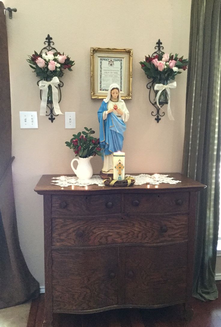 a statue of the virgin mary on top of a dresser