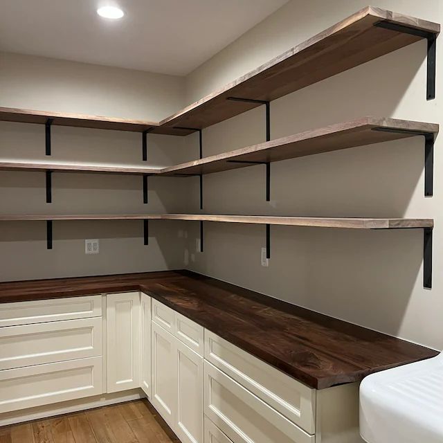 an empty room with some shelves on the wall and wood flooring in front of it