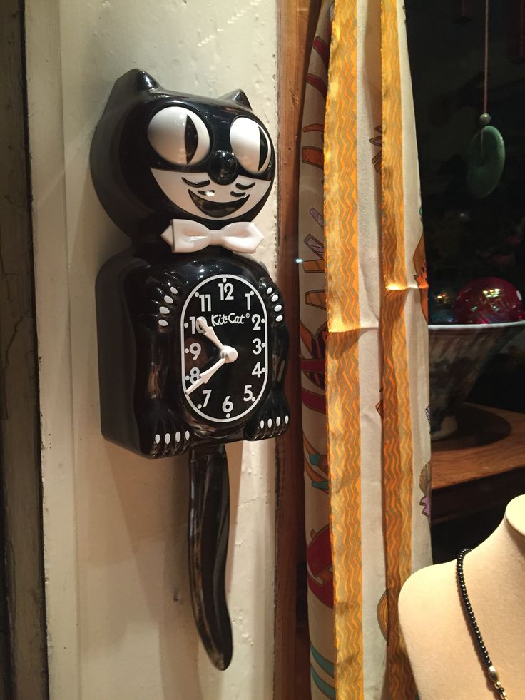 a black and white cat clock mounted to the side of a wall next to a mannequin