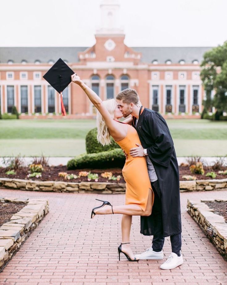 a man and woman kissing in front of a building with a graduation cap on their head