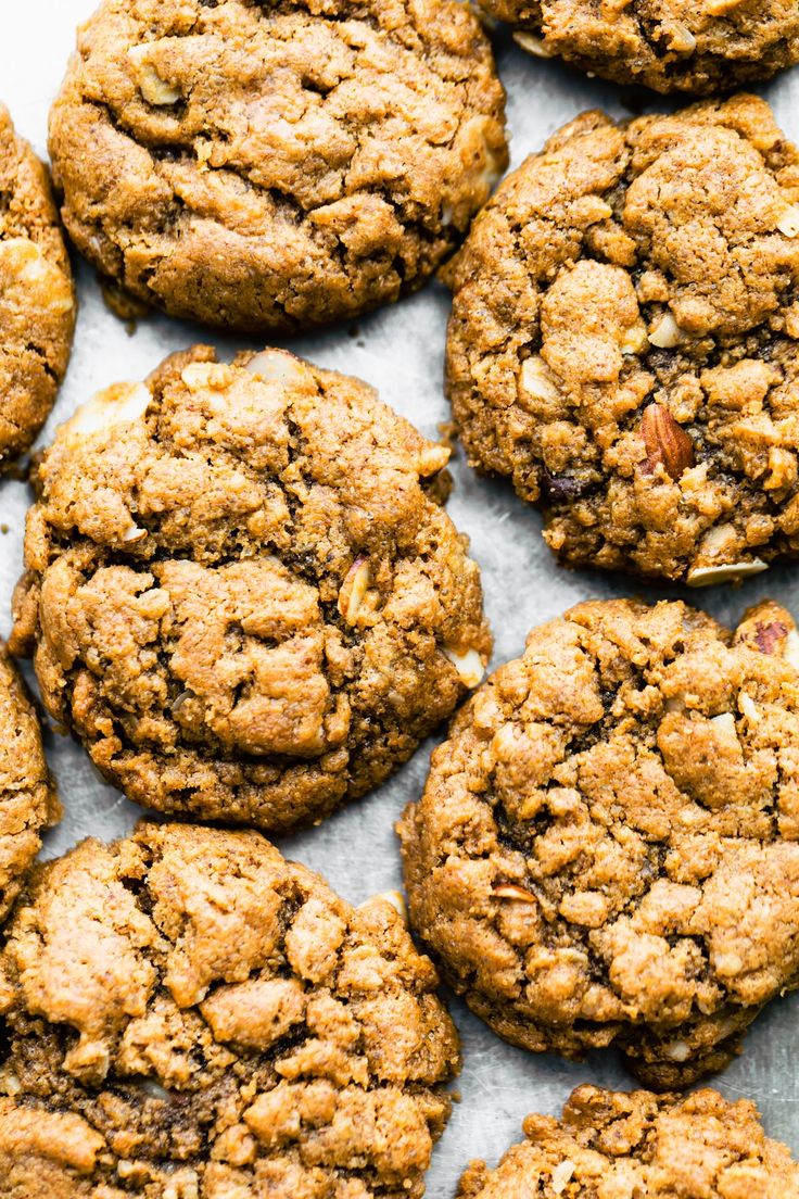 several cookies are arranged on a sheet of parchment paper with crumbled edges and pecans in the middle