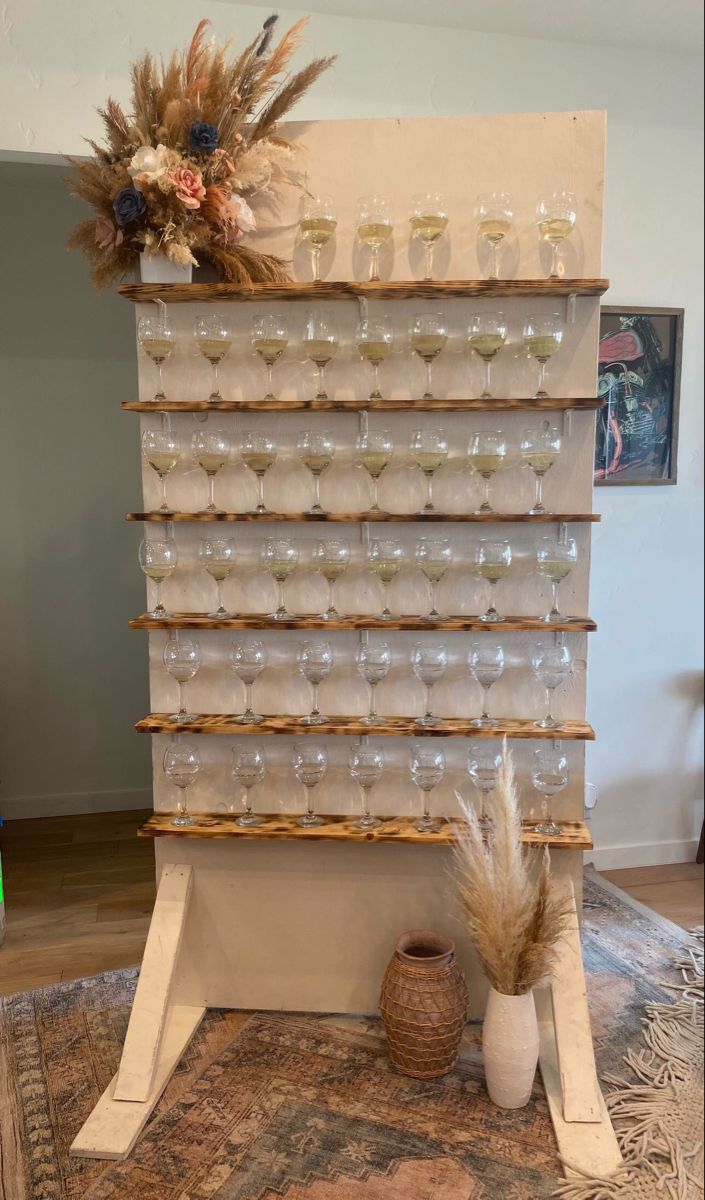 a wine rack with many glasses on it and a vase in front of the display