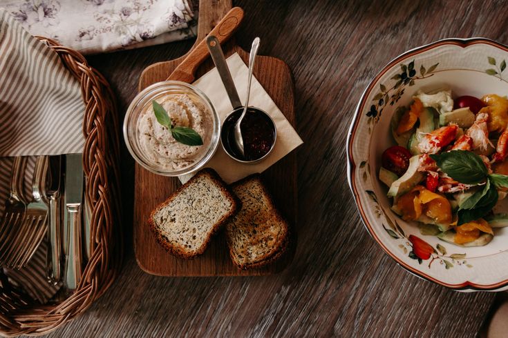 a table topped with plates and bowls filled with food next to utensils on wooden cutting boards