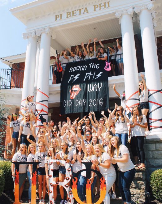 a group of people posing for a photo in front of a building with a sign