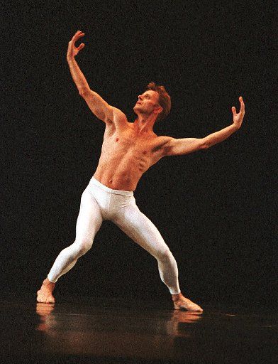 a man in white pants and no shirt standing on a stage with his arms outstretched