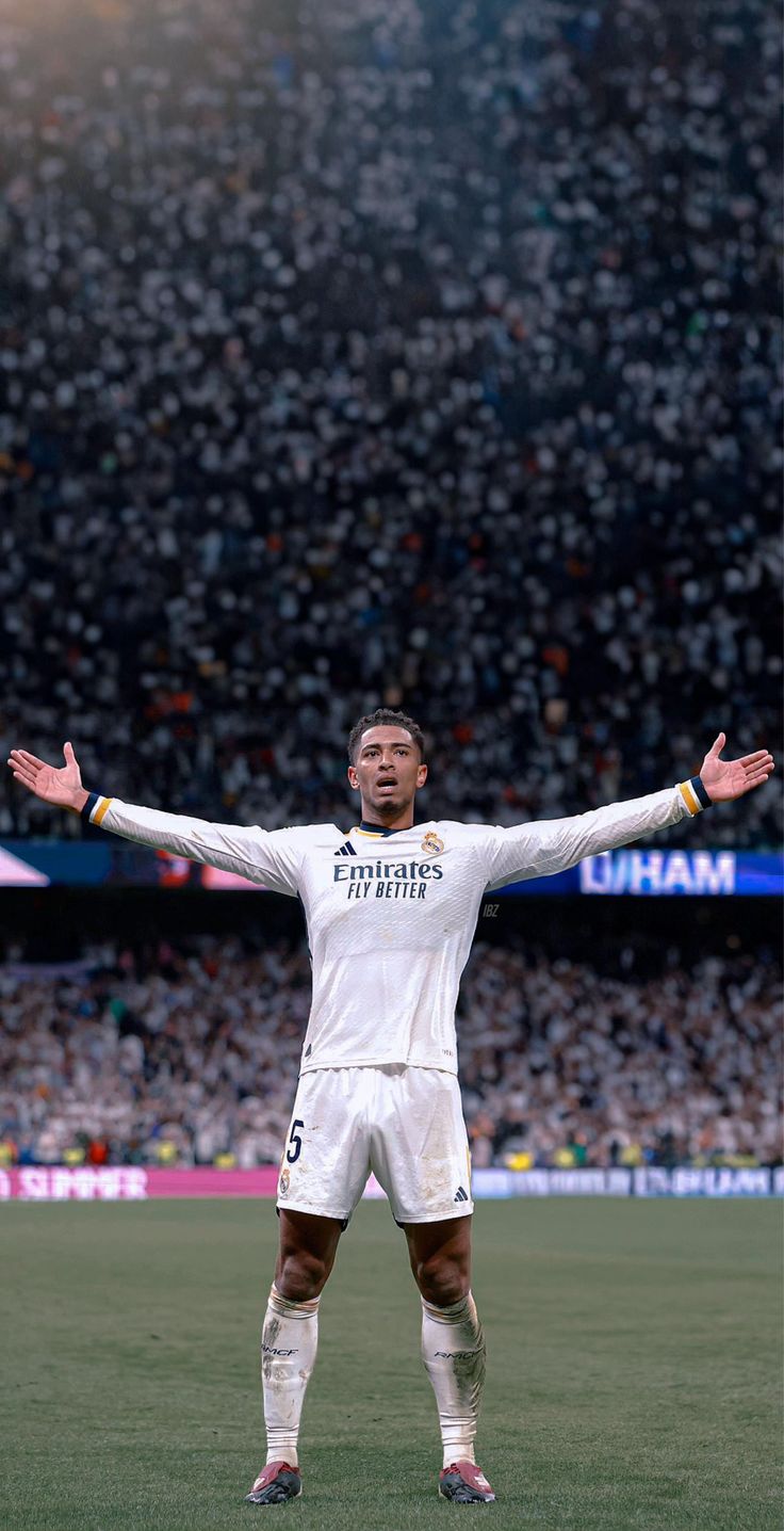 a man standing on top of a soccer field holding his arms out in front of him