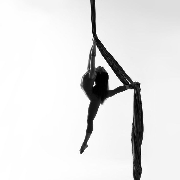 a woman is doing aerial acrobatic tricks on the pole in black and white