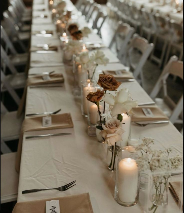 a long table is set with candles and flowers in vases on the tables, along with place settings