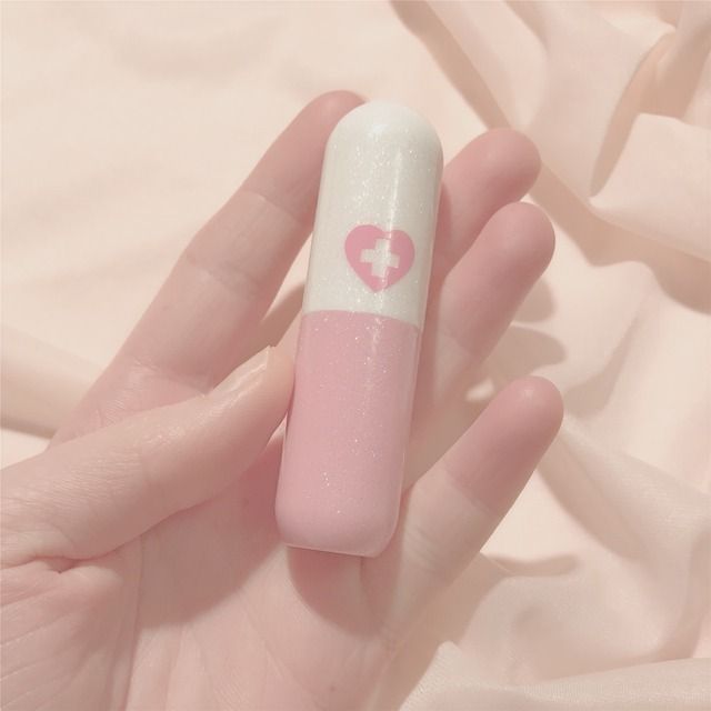 a hand holding a pink and white tube with a heart on it