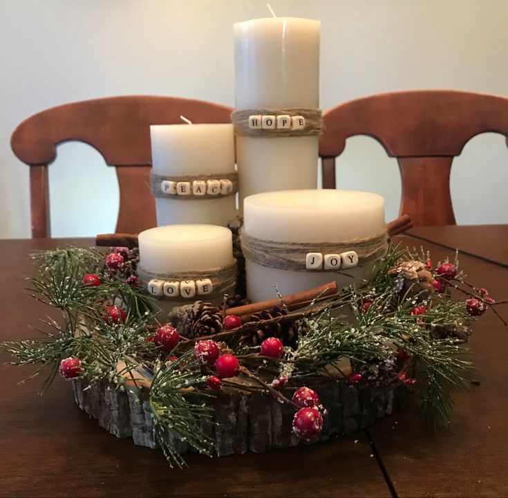 some candles are sitting on a table with pine branches and berries around it, surrounded by other christmas decorations