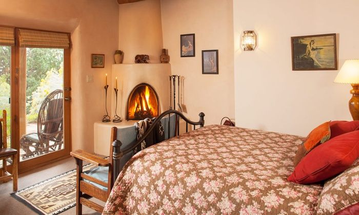 a bedroom with a fireplace in the corner and lots of pillows on the bedspread