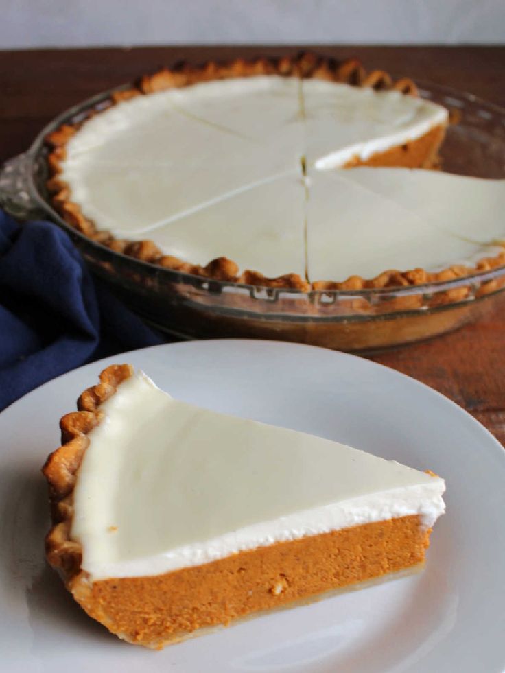 a slice of pumpkin pie on a white plate next to a glass pie dish with the rest of the pie in it