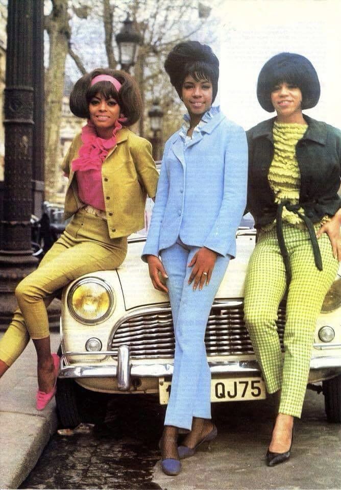 three women sitting on the hood of a car