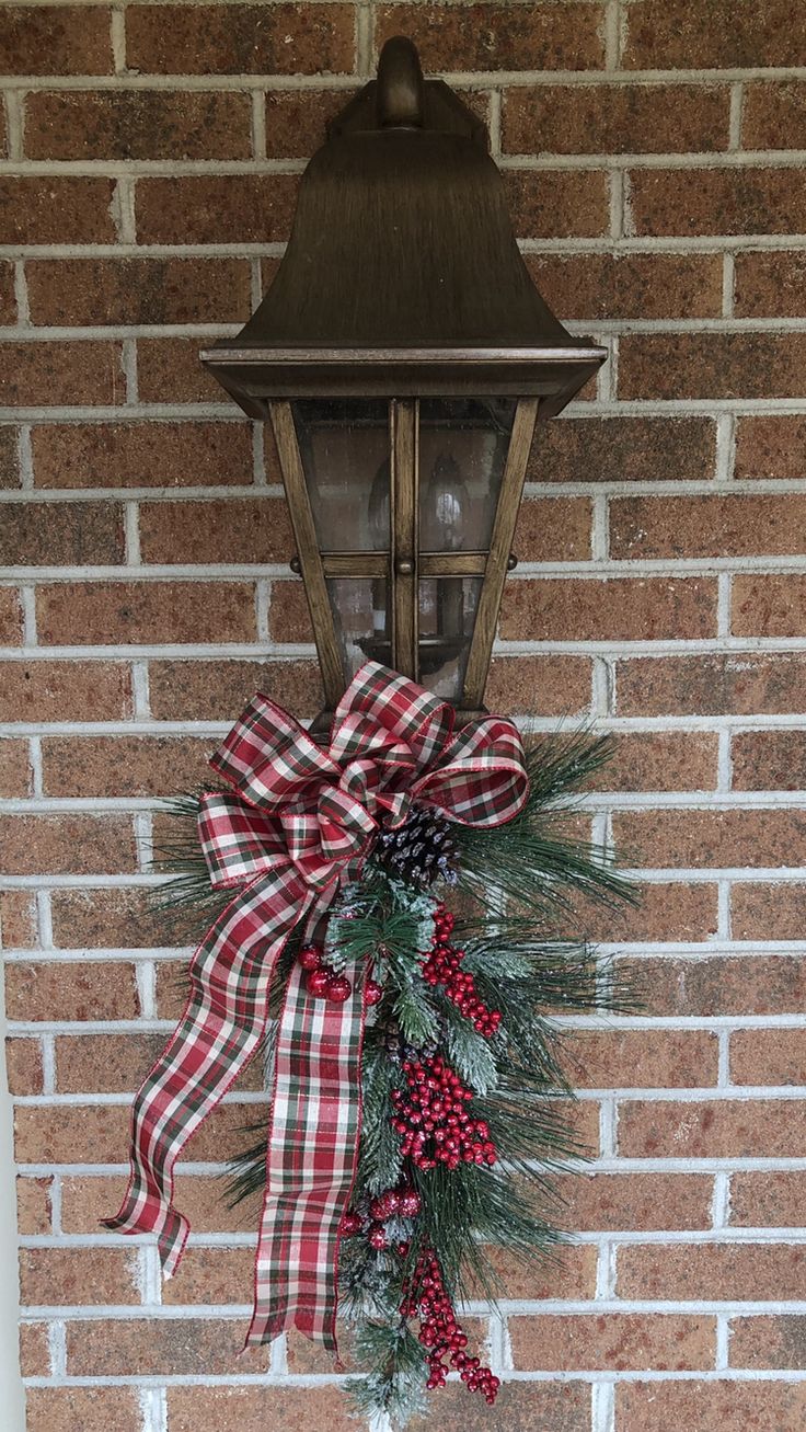 a christmas wreath hanging on the side of a brick wall next to a lamp post