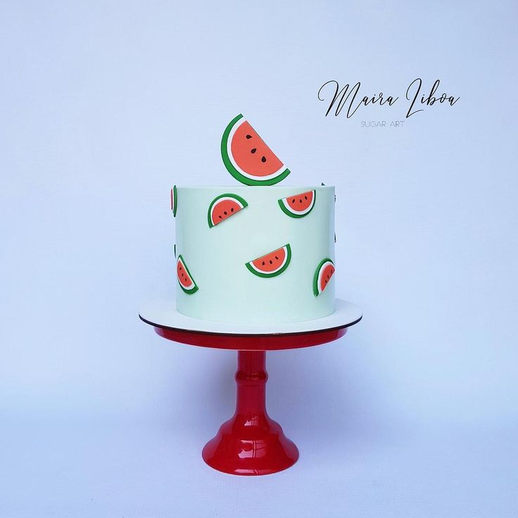 a cake with watermelon slices on it sitting on top of a red stand