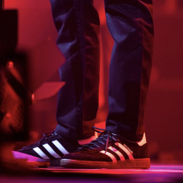 a person standing on top of a stage wearing black and white shoes with purple lighting behind them