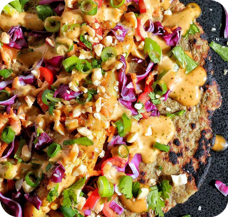 a pizza topped with lots of toppings on top of a black plate next to other food