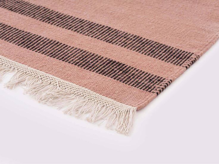 a pink and black checkered rug with tassels on the bottom, sitting on a white surface