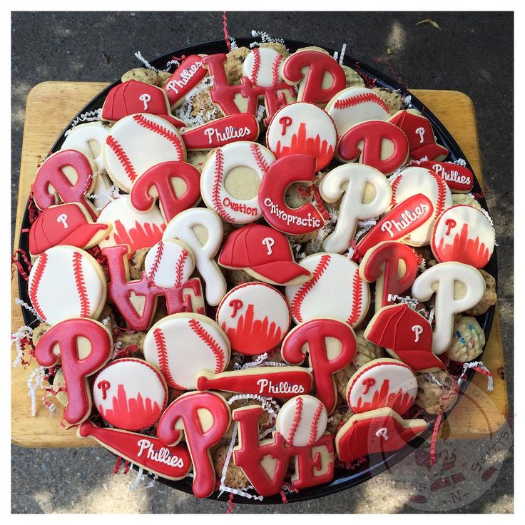 decorated cookies in the shape of baseballs and bats are on a platter for display