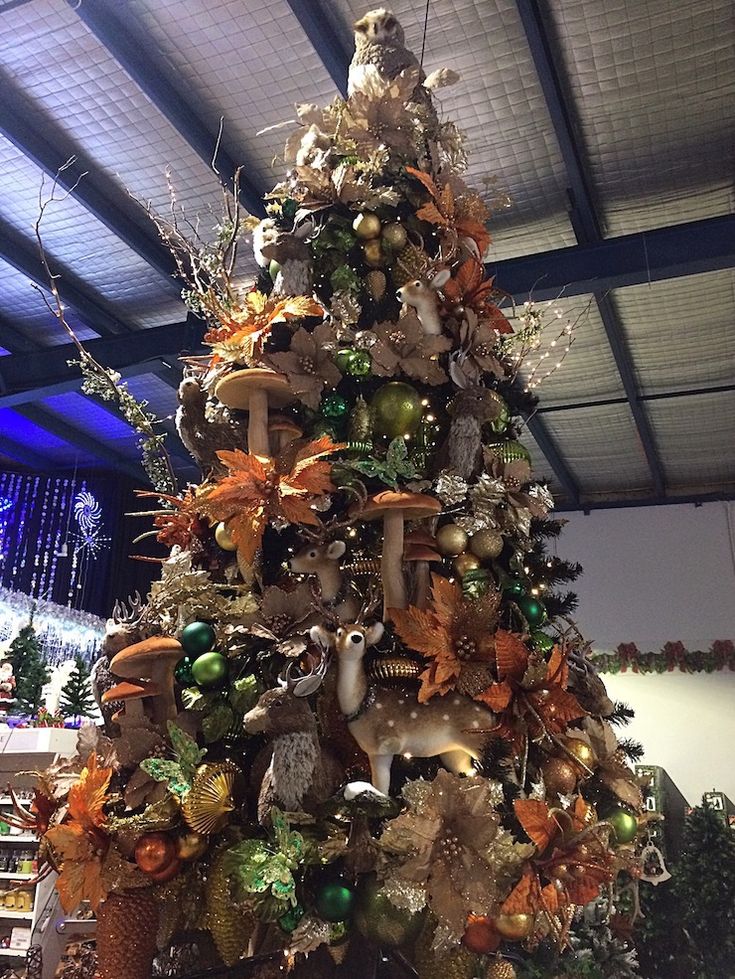 a decorated christmas tree with deers and other ornaments on it's sides in a building