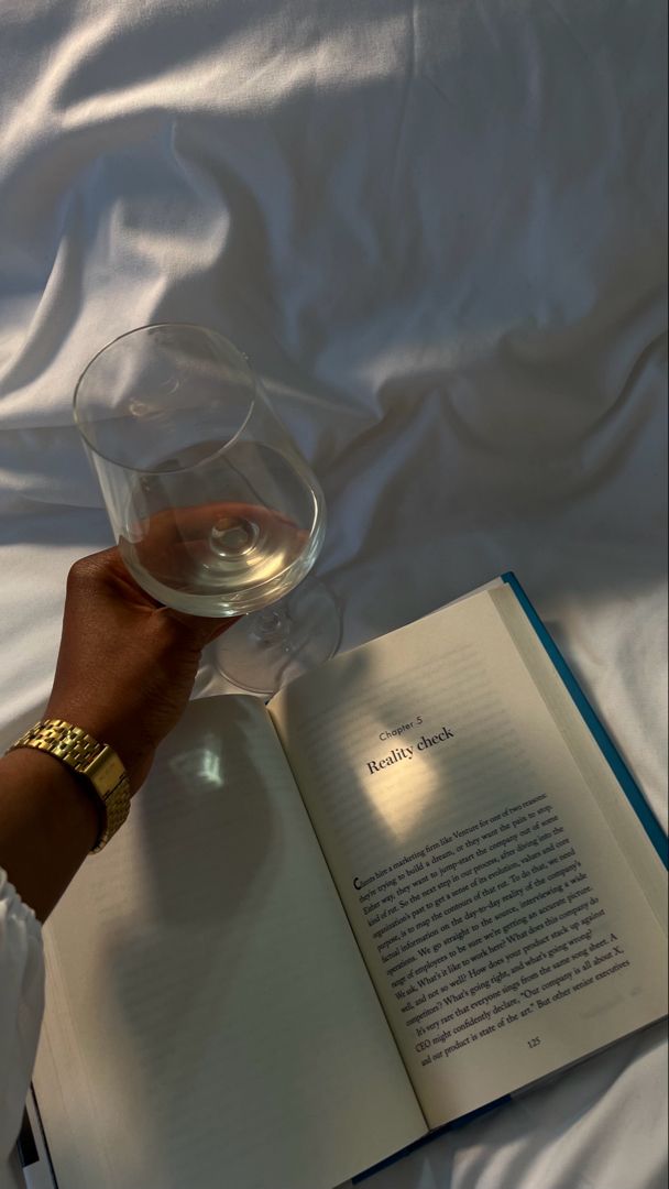 an open book and a wine glass on a bed