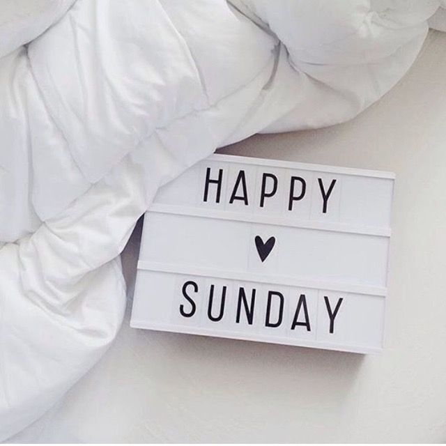 a happy sunday sign sitting on top of a white pillow next to a pile of pillows