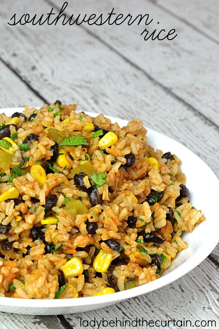 a white bowl filled with rice and beans on top of a wooden table next to a fork