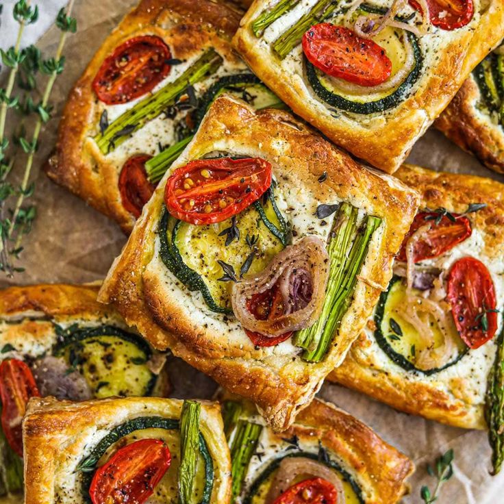 several square sandwiches with tomatoes, asparagus and other toppings on top of them