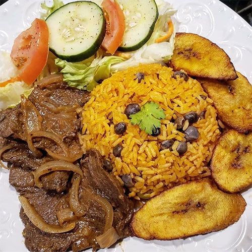 a white plate topped with meat, rice and veggies next to sliced cucumbers